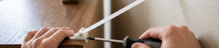 Anti-tip strap connecting the back top edge of a dresser to the wall